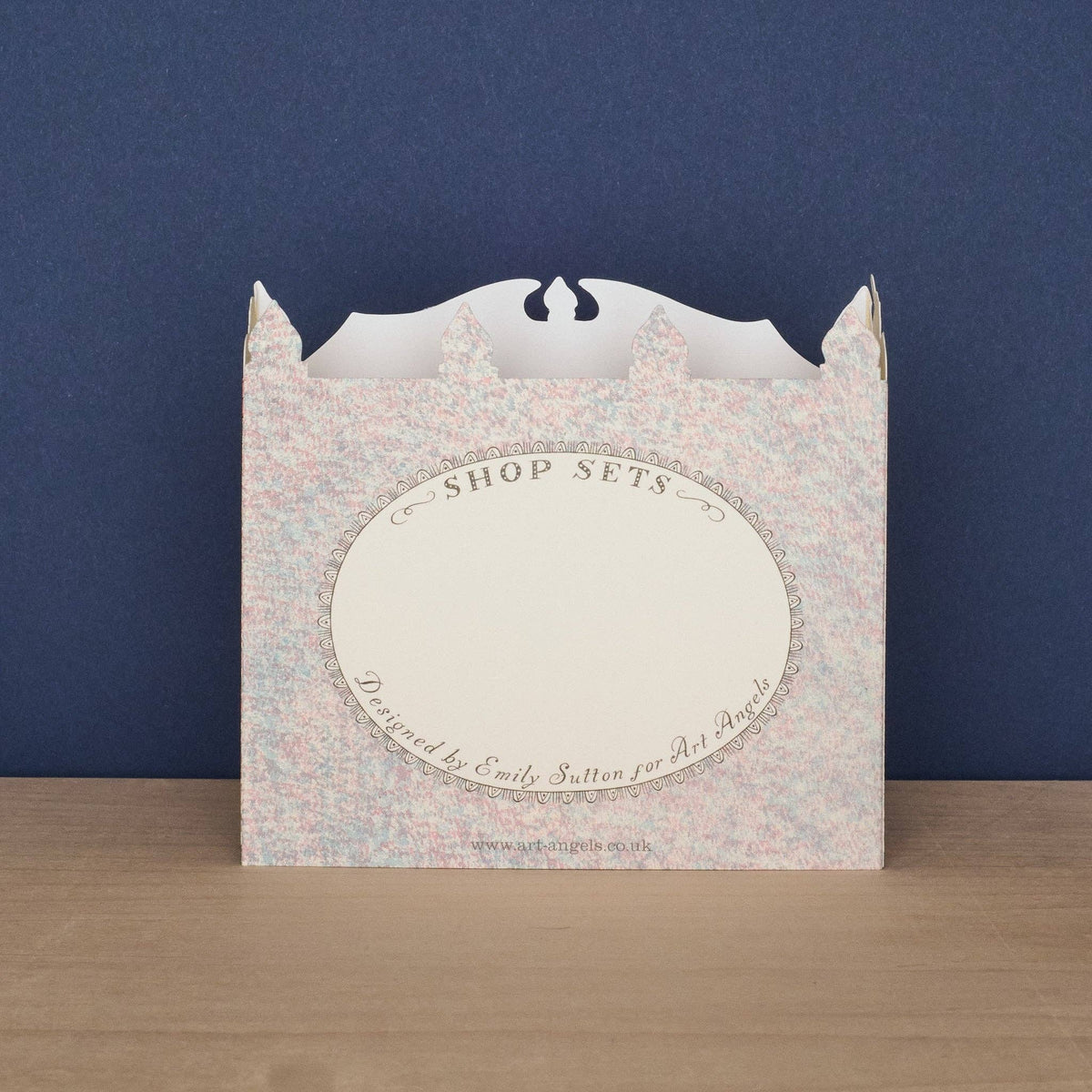 Packaging box with floral pattern and text on a wooden surface and blue background