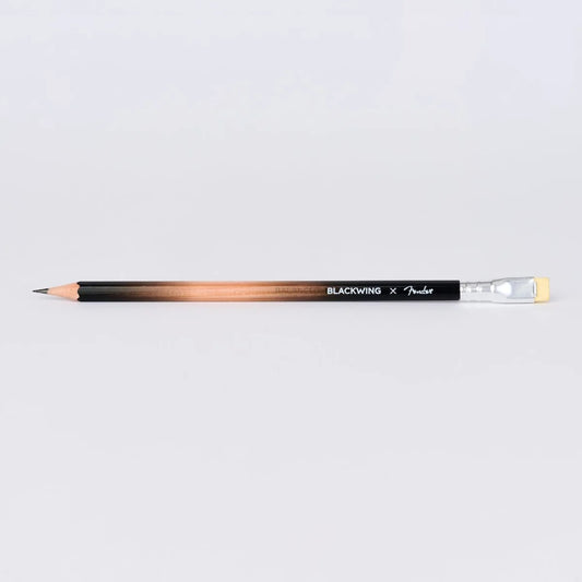A Fender x Blackwing graphite pencil with a black-to-copper gradient barrel, shown horizontally on a light gray background.