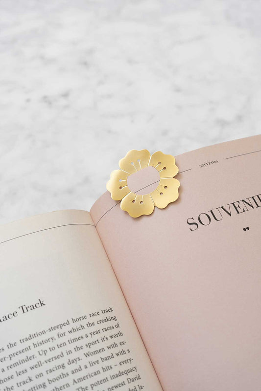 Gold flower-shaped bookmark on an open book with 'Souvenir' text.