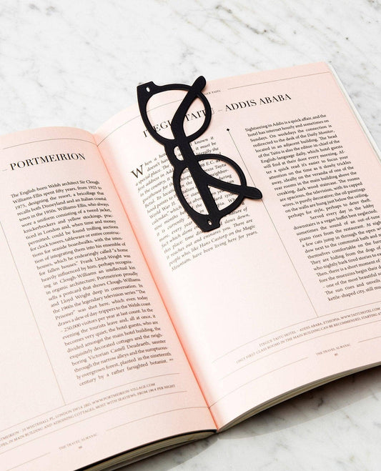 Black eyeglasses-shaped bookmark on an open book