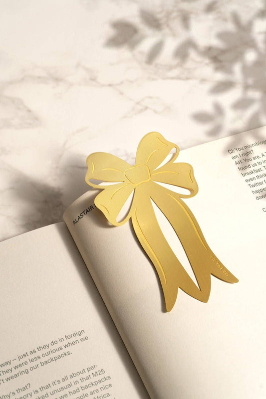 Gold bow-shaped bookmark on an open book with a soft background