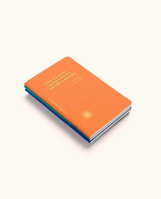 A stack of three hardcover books, with the top book in bright orange showing the title 'There is no secret or hidden weapon in terror or hatred' and a small gold seal. The books are stacked diagonally on a light cream background.
