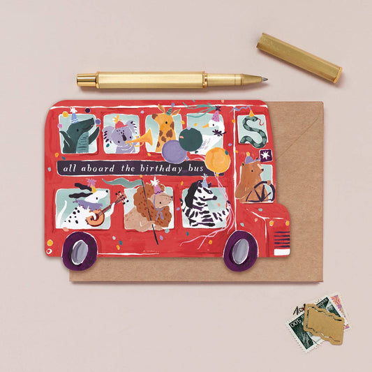 Greeting card with a red bus design featuring animals and text, on a beige background.