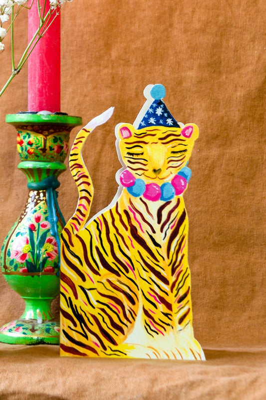 Colorful tiger figurine with a party hat on a wooden surface