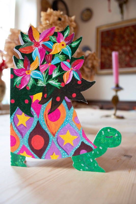 Colorful paper cutout of a cat with floral patterns on a wooden surface.