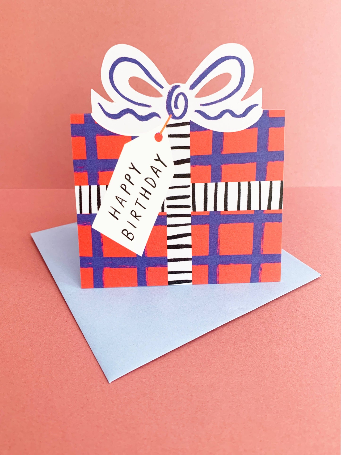 Birthday card with a plaid gift box design and 'Happy Birthday' tag on a pink background