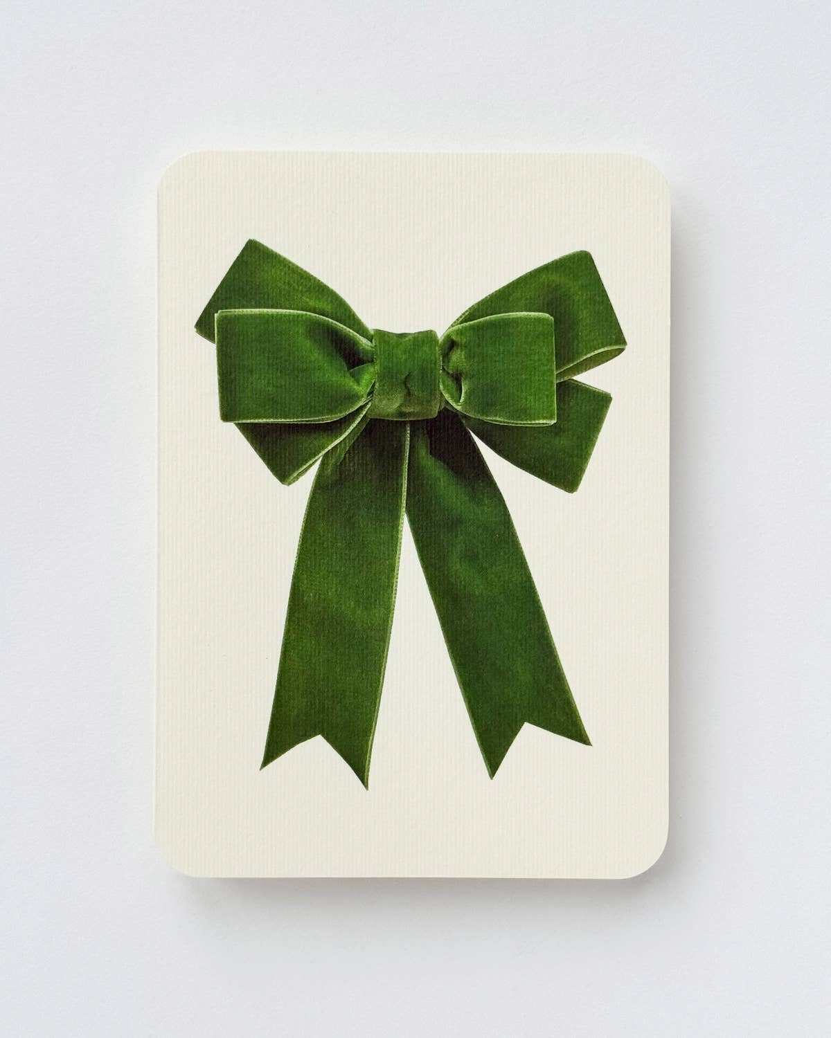 Green velvet bow on a white card with a light gray background