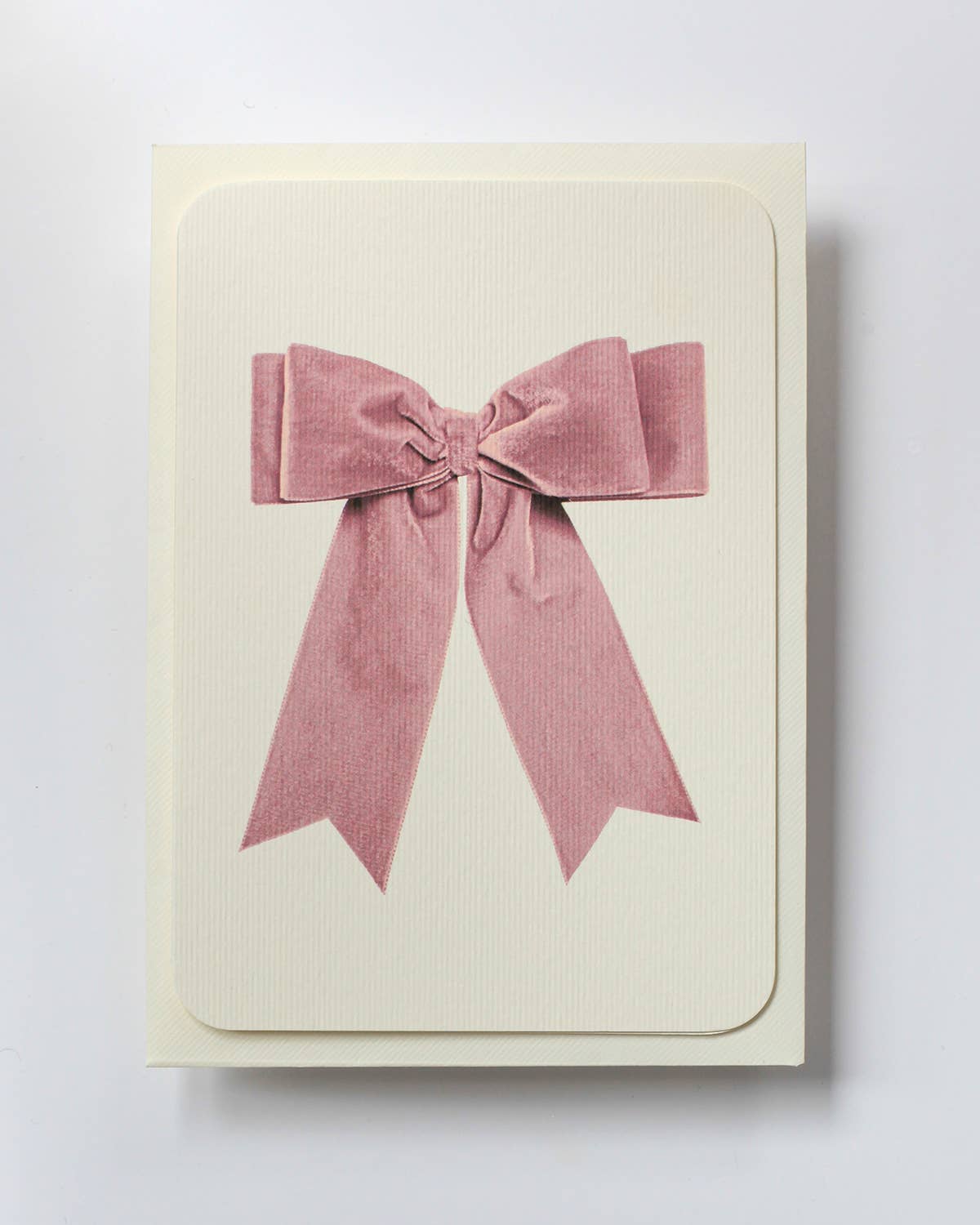 Beige card with a large pink bow on a white background