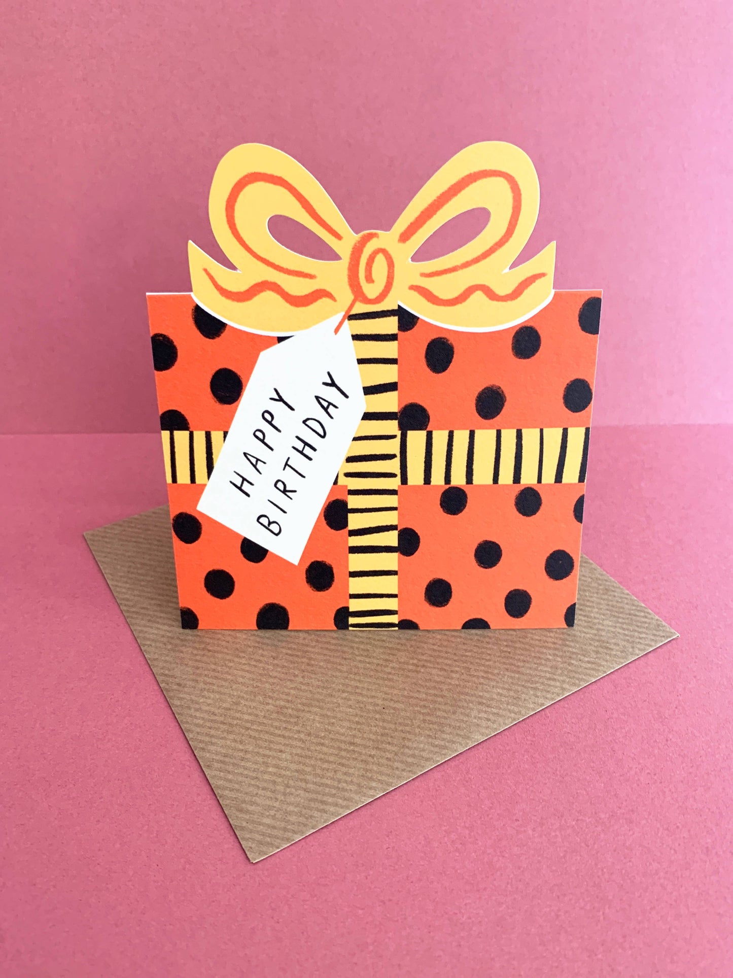 Handmade birthday card with polka dot present design and yellow ribbon on a pink background