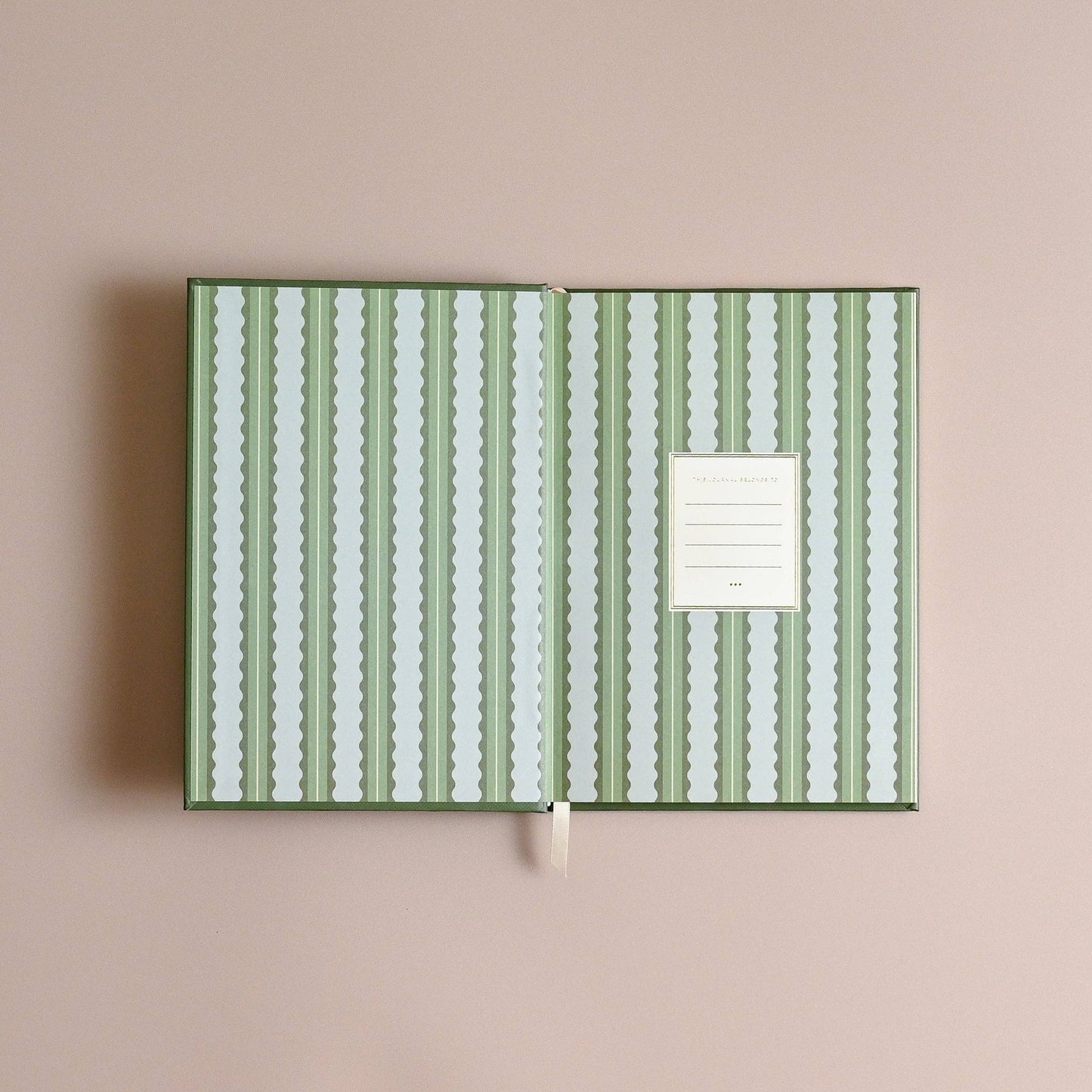Notebook with green and white striped cover on a beige background