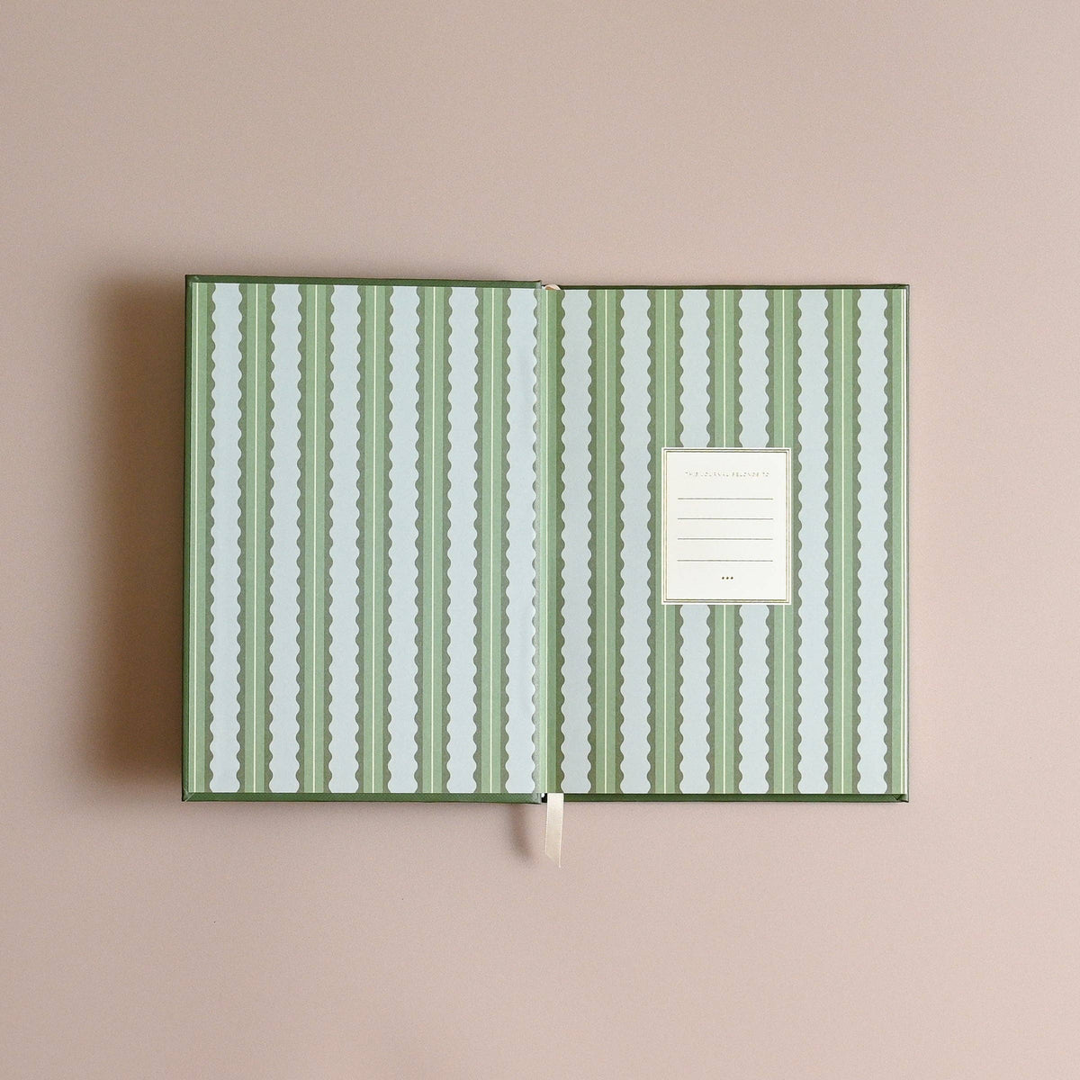 Notebook with green and white striped cover on a beige background