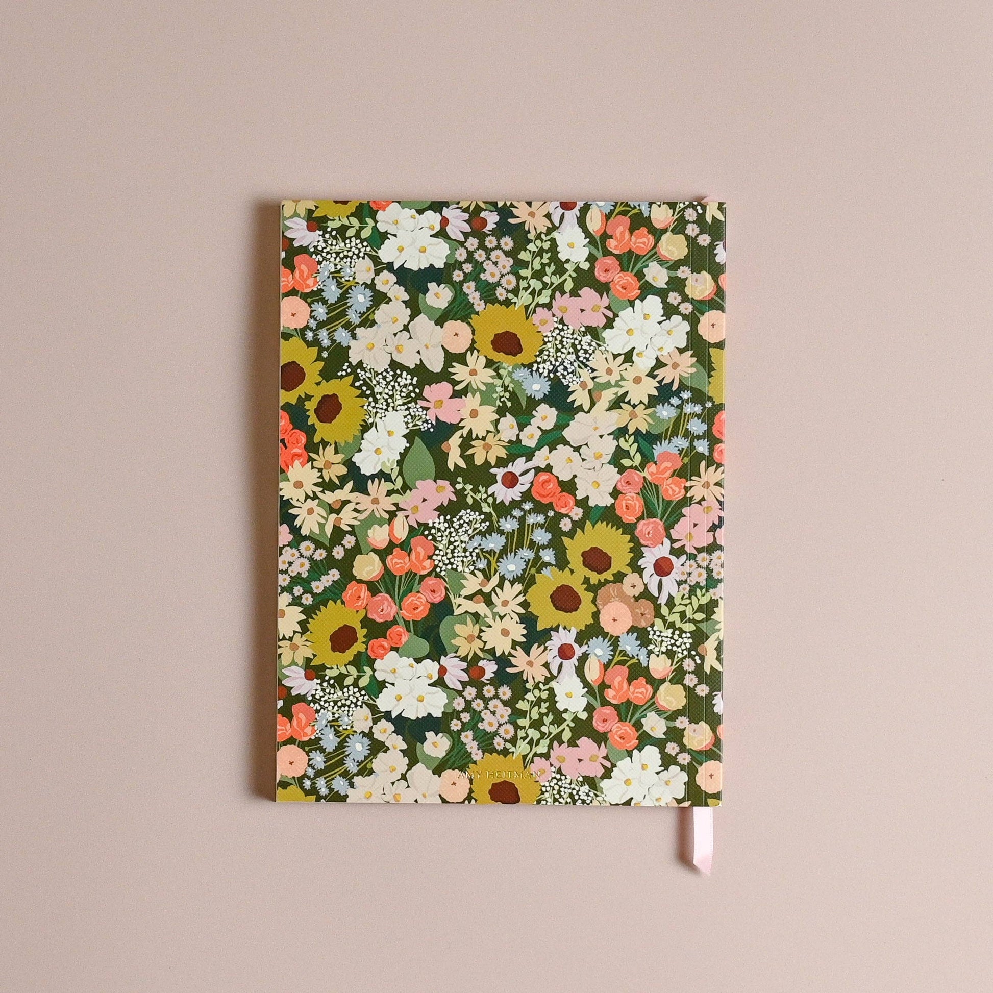 A floral patterned notebook with a pink ribbon bookmark, displayed flat against a solid beige background.