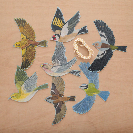 Colorful paper bird cutouts on a wooden surface with string.