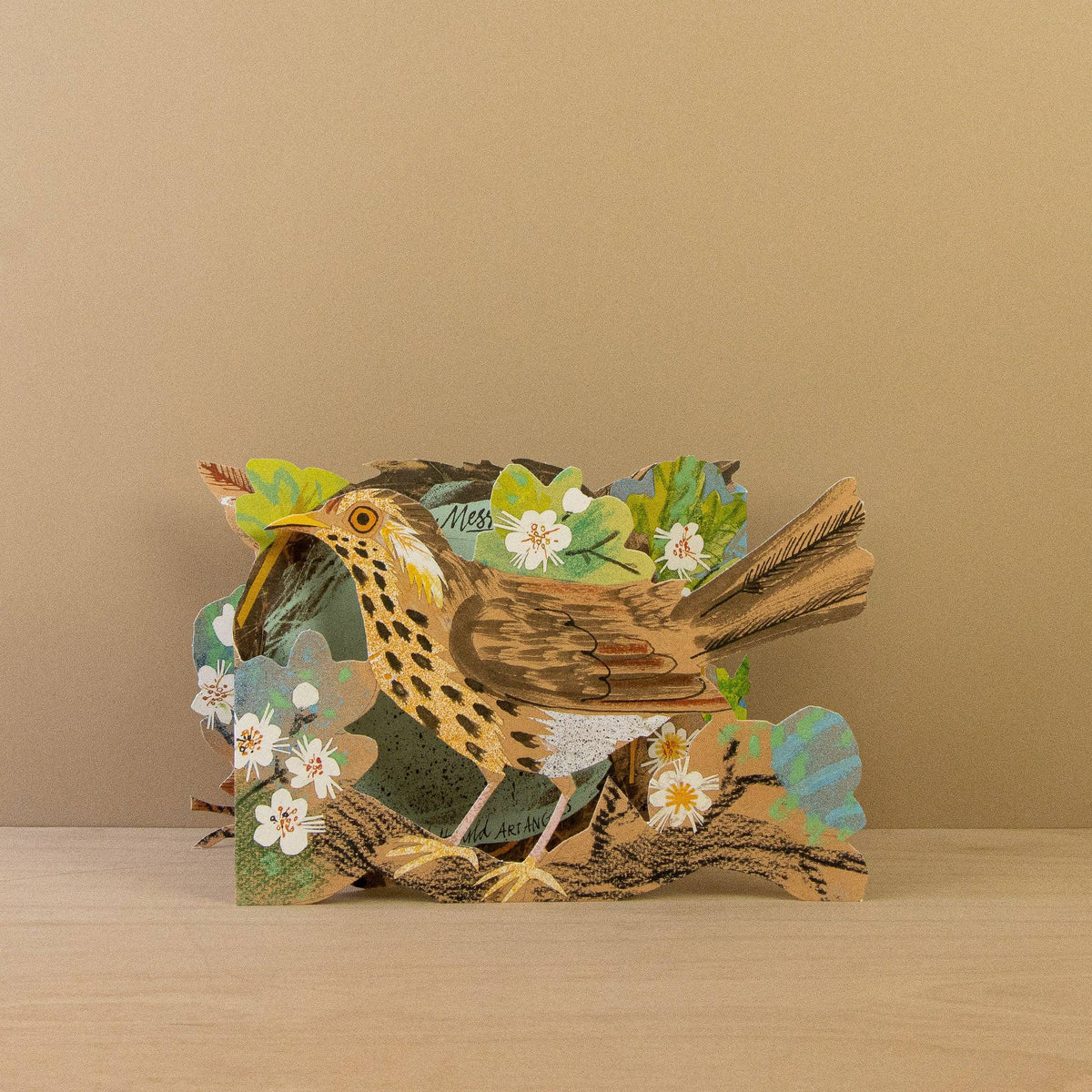 Card with a 3D bird design on a wooden surface and beige background