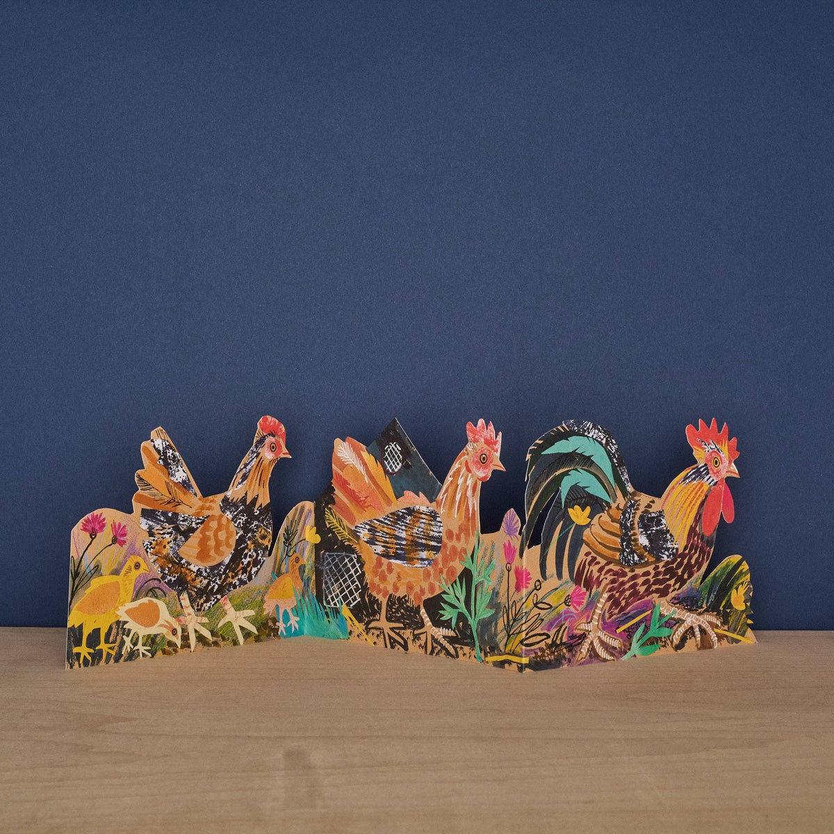 Decorative set of colorful roosters on a wooden surface with a blue background
