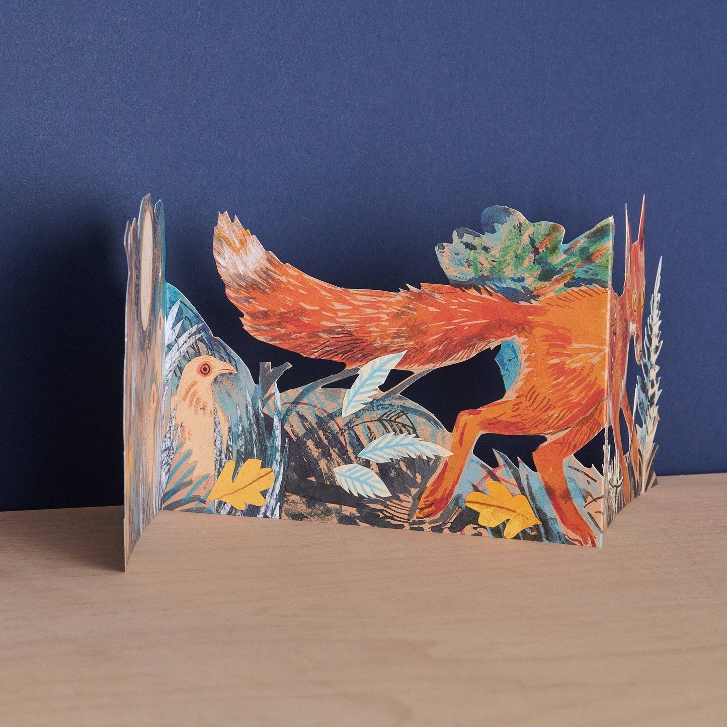 Pop-up card with a fox design on a wooden surface and blue background