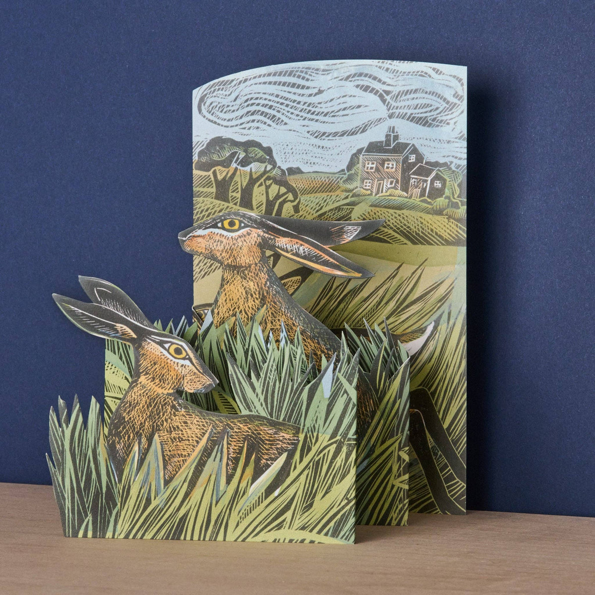 Pop-up book with hares and landscape design on a wooden surface and blue background