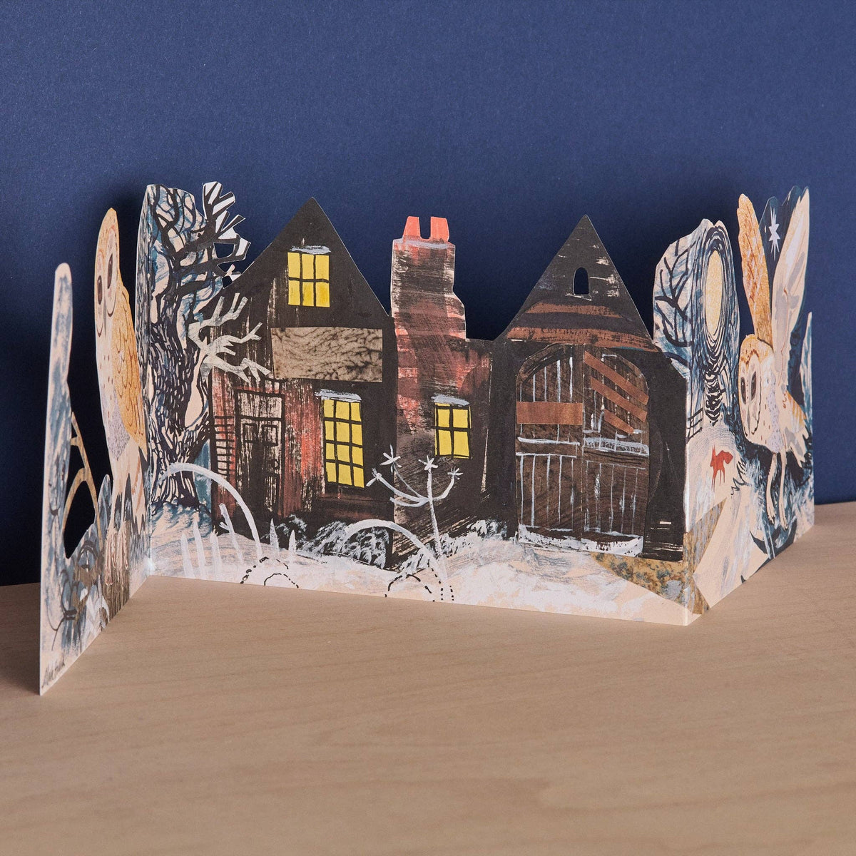 Pop-up card with winter scene featuring houses and trees on a blue background