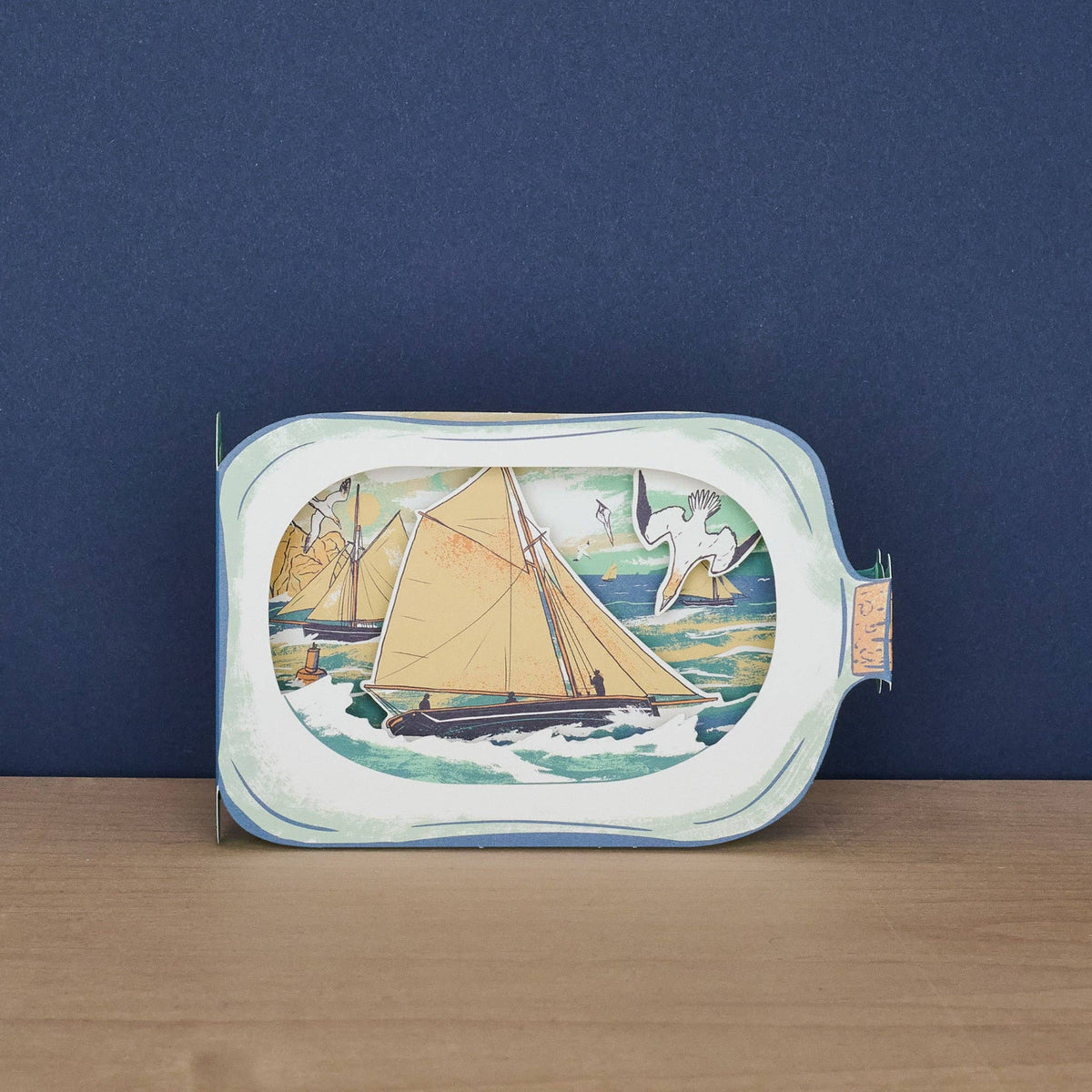 Decorative tray with a sailboat design on a wooden surface and dark blue background