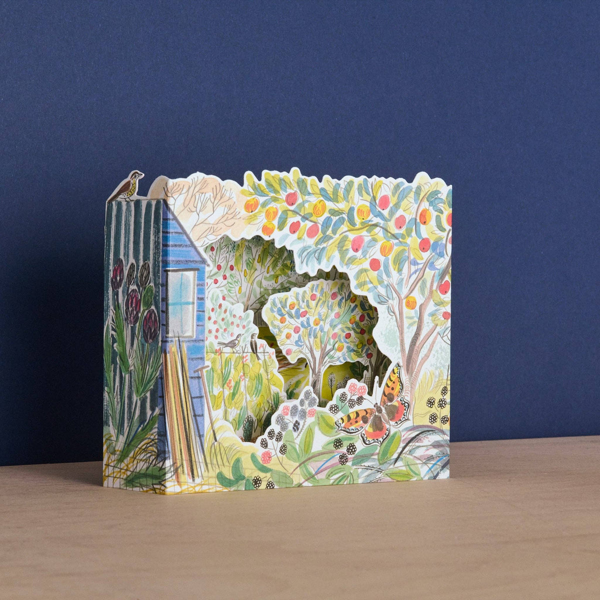 Pop-up card with nature-themed design on a wooden surface and dark blue background