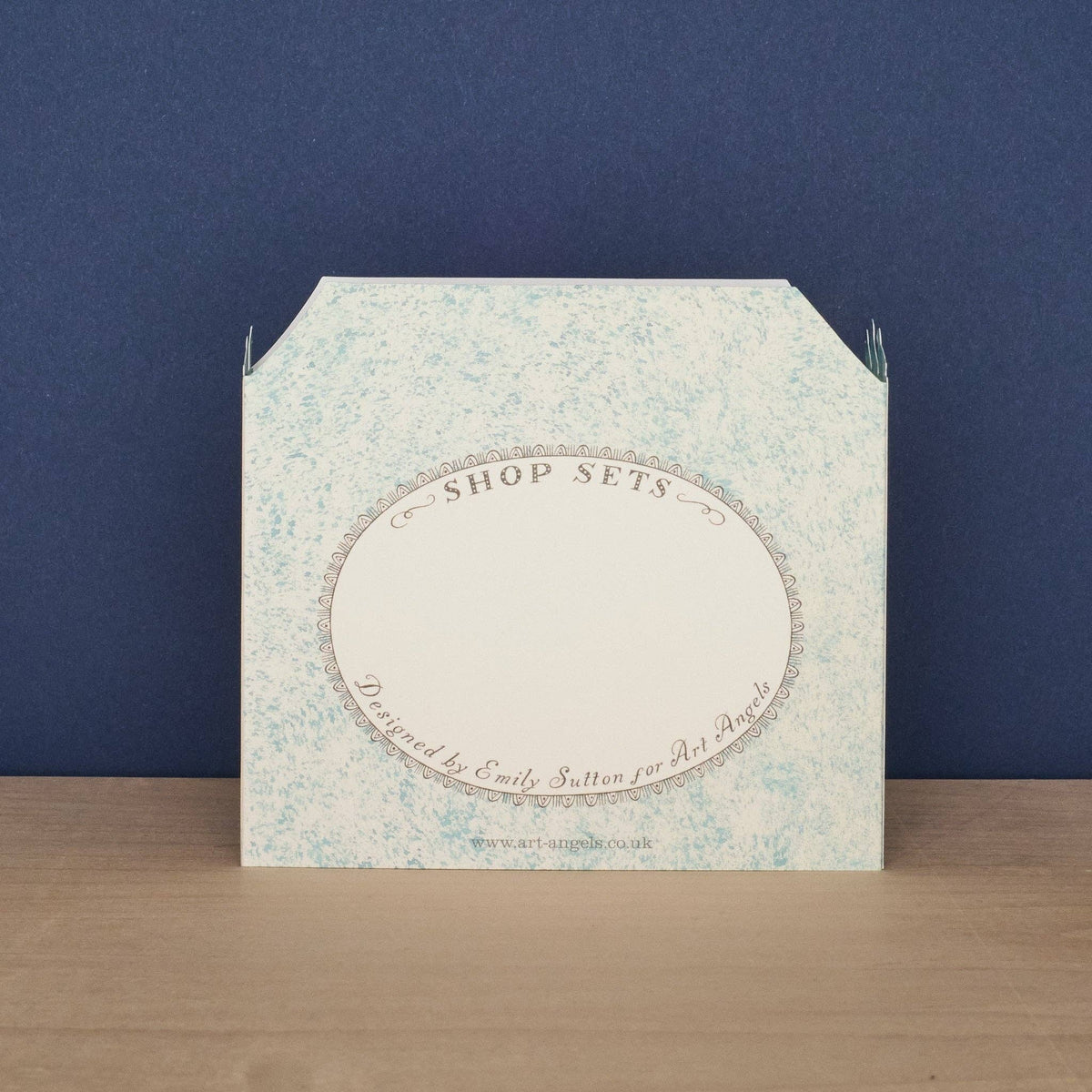 Packaging box with floral design and text on a wooden surface and blue background