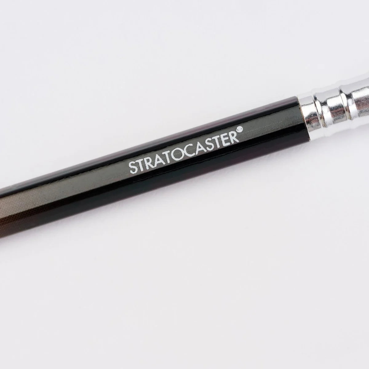 A close-up of a paintbrush handle with the brand name 'STRATOCASTER' printed in white on a glossy black grip, with a silver ferrule visible at the top right, set against a plain white background.