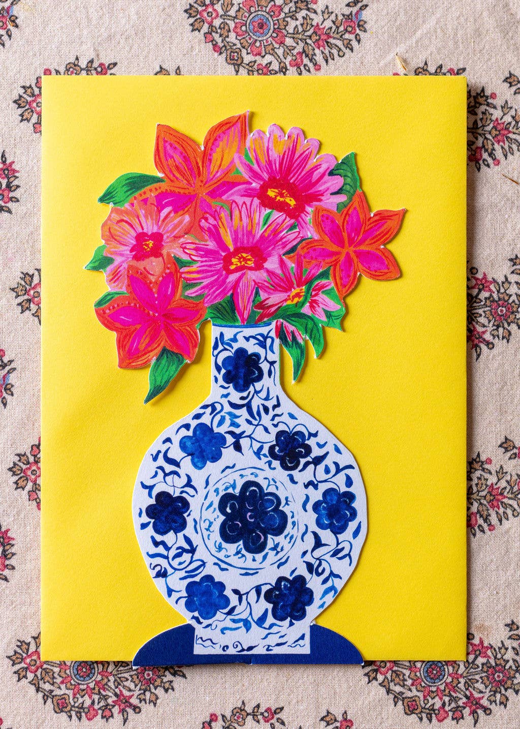 Colorful floral design on a yellow background with a blue and white vase.