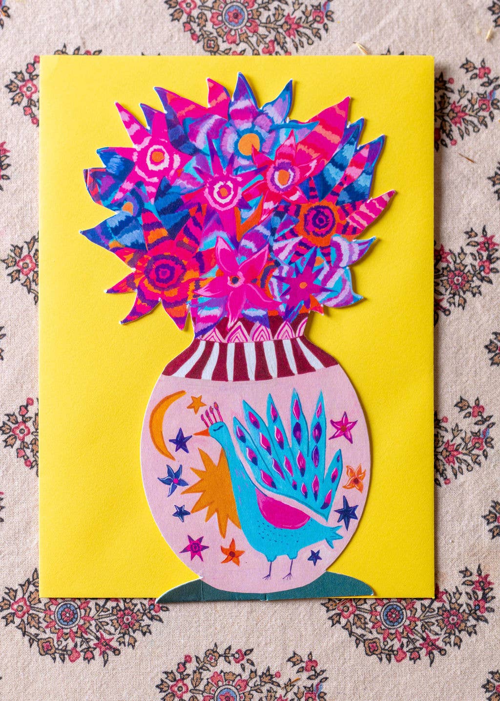 Colorful vase with peacock design and floral patterns on a yellow background