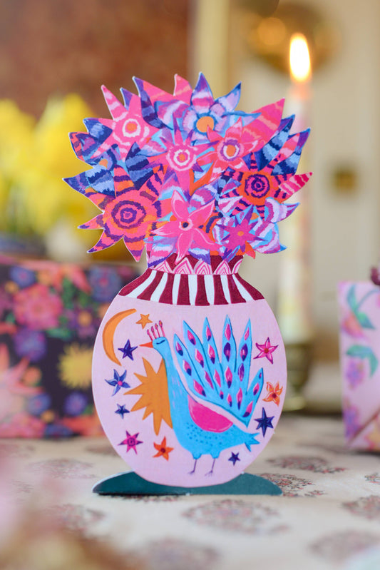 Colorful decorative item with peacock design on a stand, blurred background