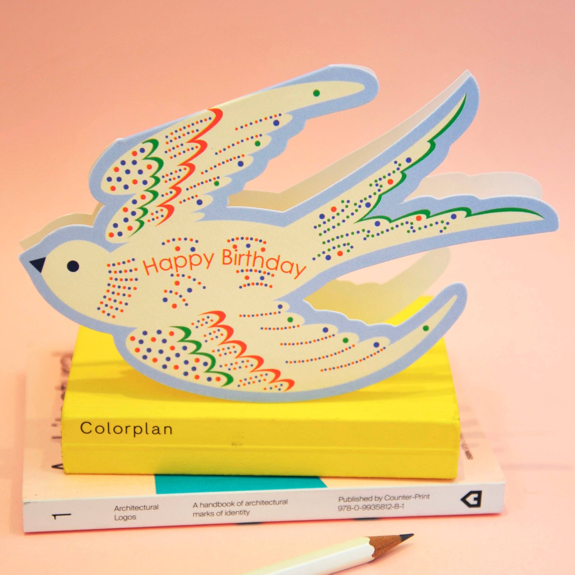 Colorful bird-shaped card with 'Happy Birthday' text on a pink background