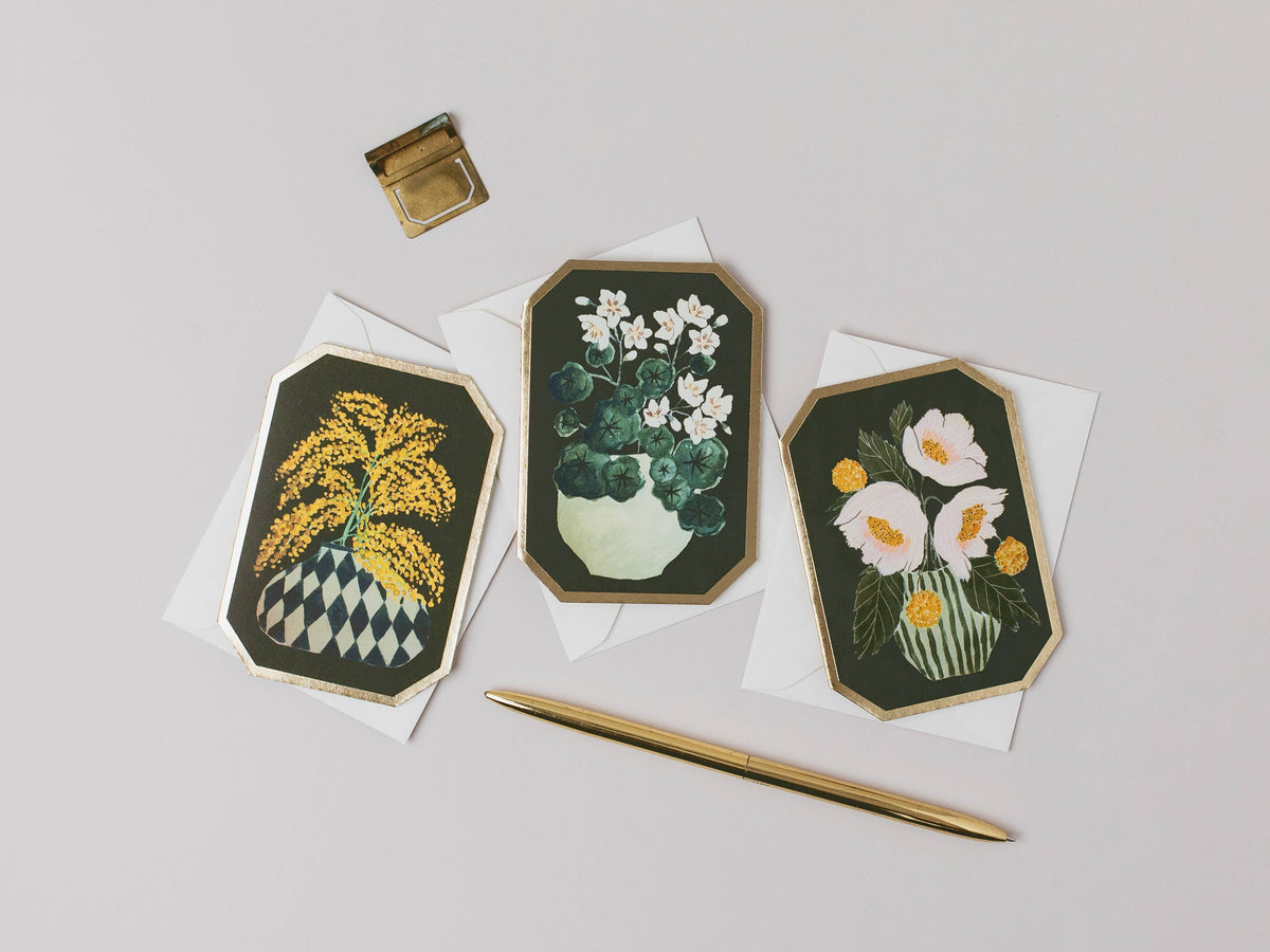 Three floral embroidered cards on white paper with a gold pen and inkwell.
