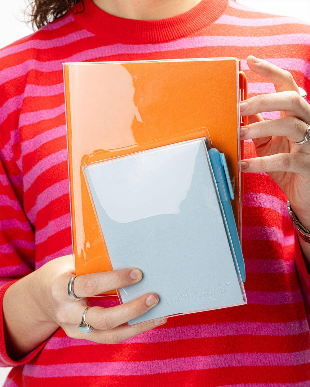 Person holding an orange notebook with a clear front cover