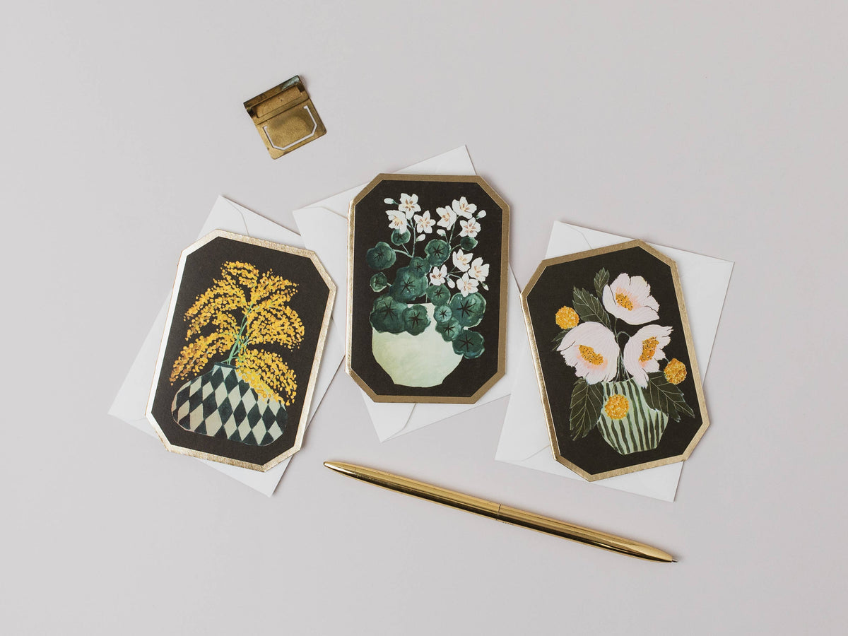 Three floral embroidered cards on white paper with a gold pen and inkwell.