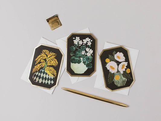Three floral embroidered cards on white paper with a gold pen and inkwell.