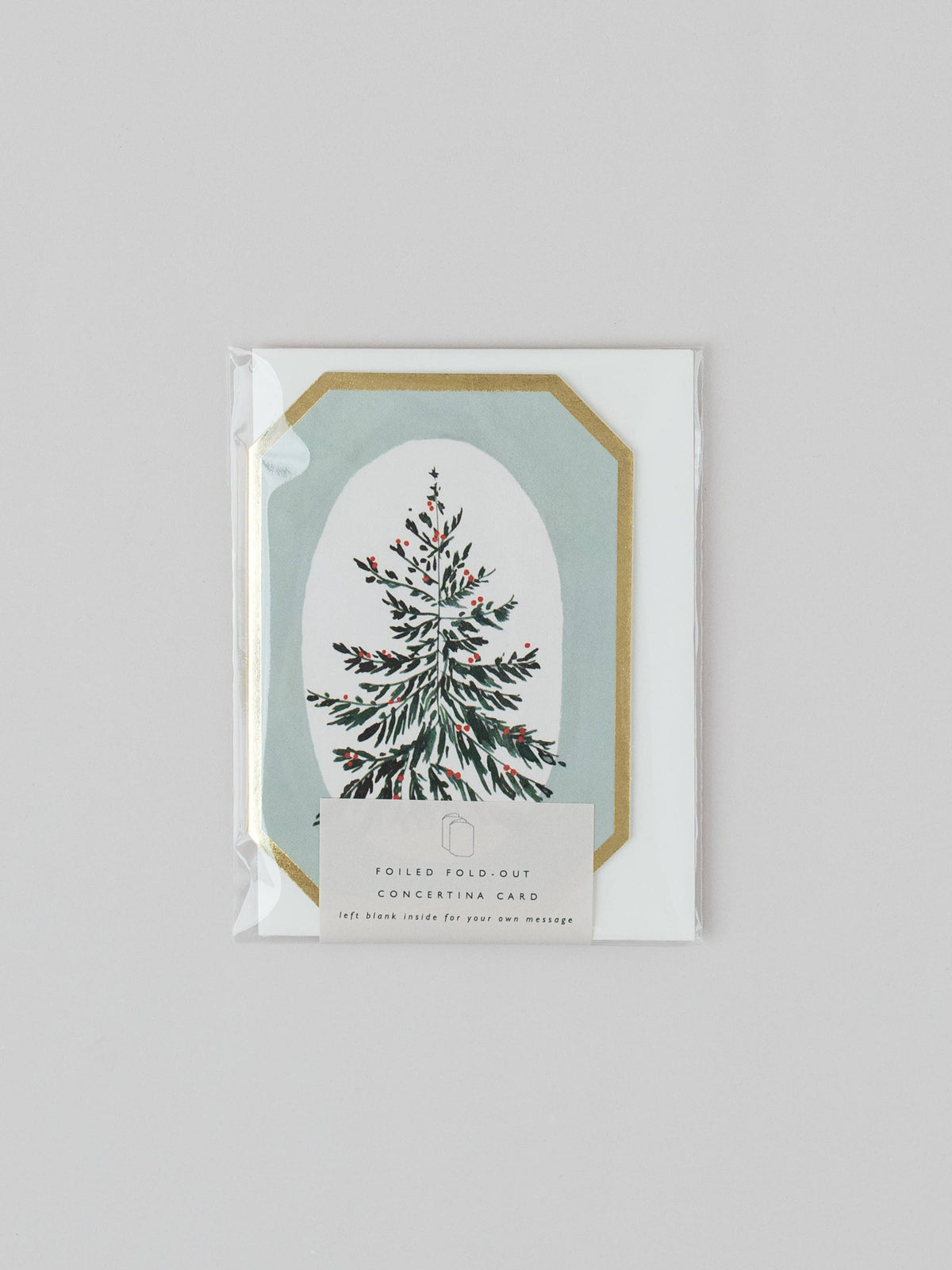 A packaged Christmas-themed folding pocket card featuring an illustrated evergreen tree inside an arched frame with a gold border on a white card, sealed in clear plastic against a light gray background.