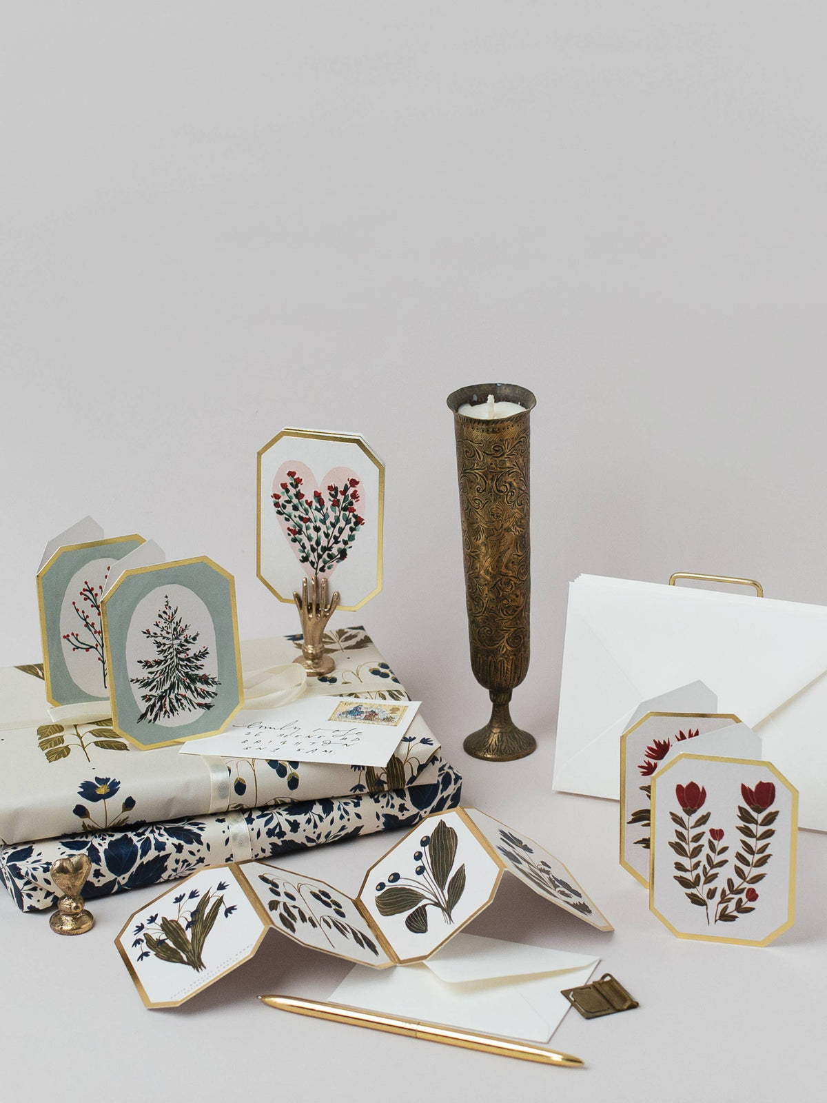 Collection of stationery items including cards, envelopes, and a candle on a light gray background