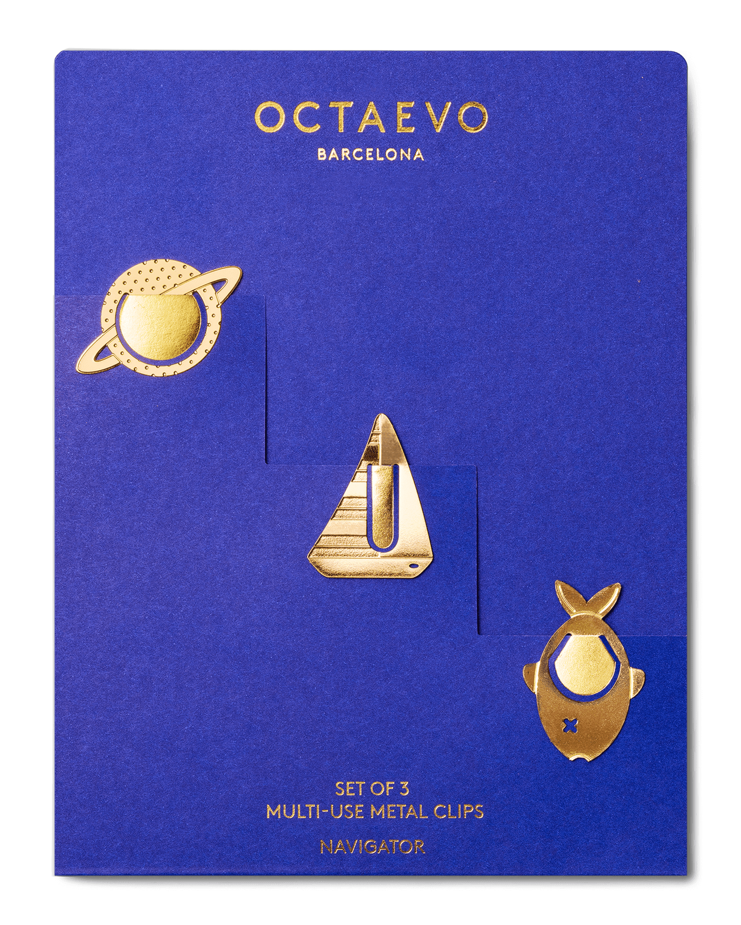 A set of three gold metal multi-use clips by Octaevo Barcelona, displayed on a blue backing card. The clips feature a planet with rings, a sailboat, and a navigator.