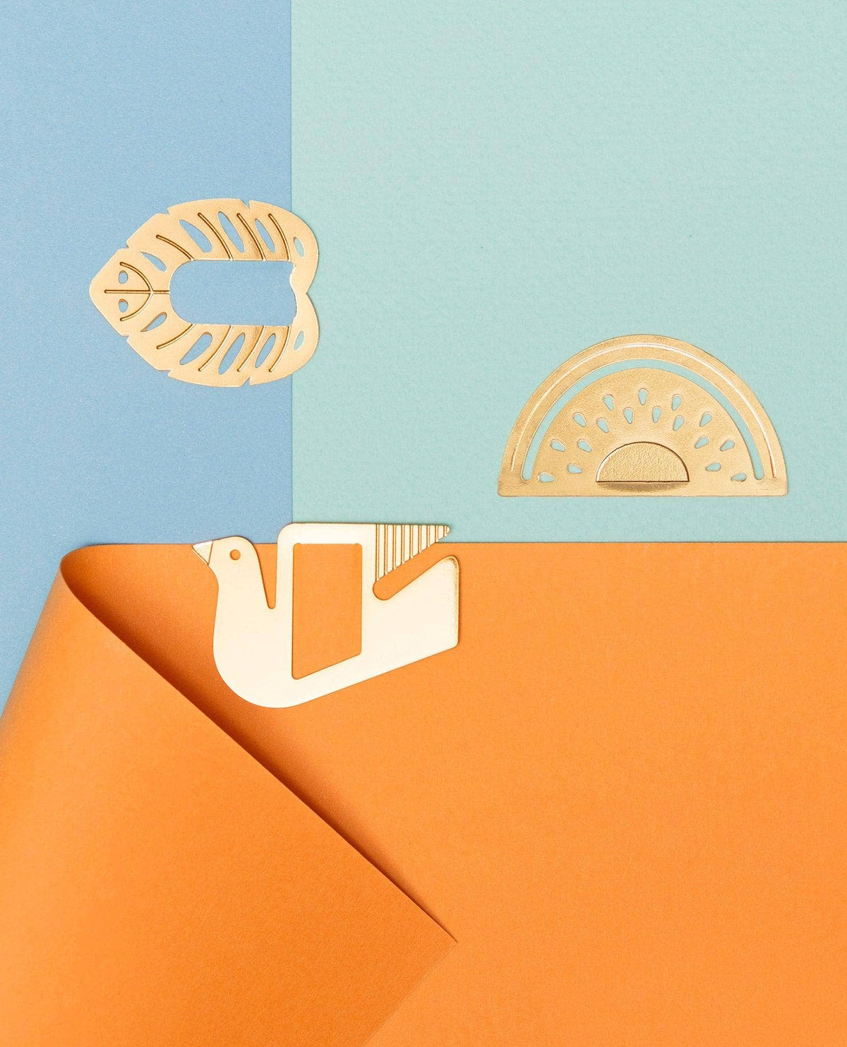 Three light wood craft cutouts, including a fish, a semicircle pattern, and a bird shape, arranged on a split blue and orange background.