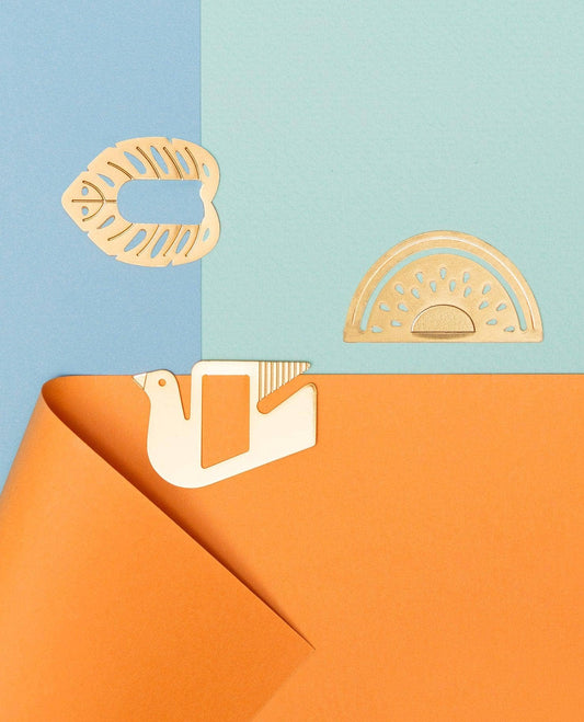 Three light wood craft cutouts, including a fish, a semicircle pattern, and a bird shape, arranged on a split blue and orange background.