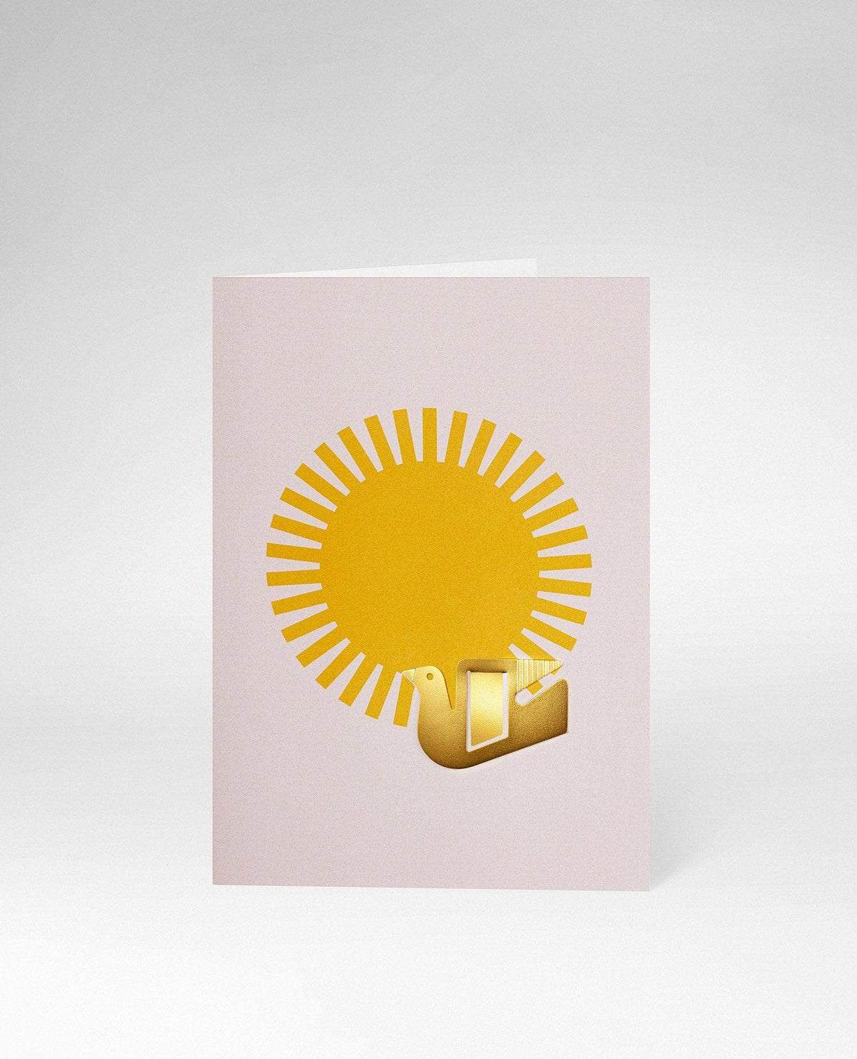 A minimalist greeting card with a pale pink background, featuring a yellow sun graphic and a small gold 3D gift box icon, shown on a light gray background.