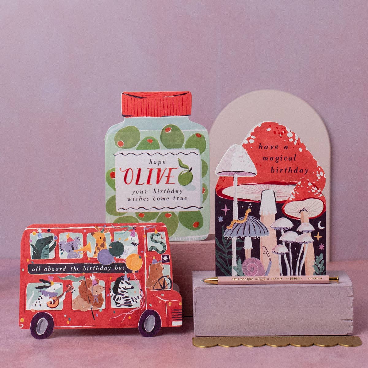 Decorative items including a small bus, bottle, and card on a pink background
