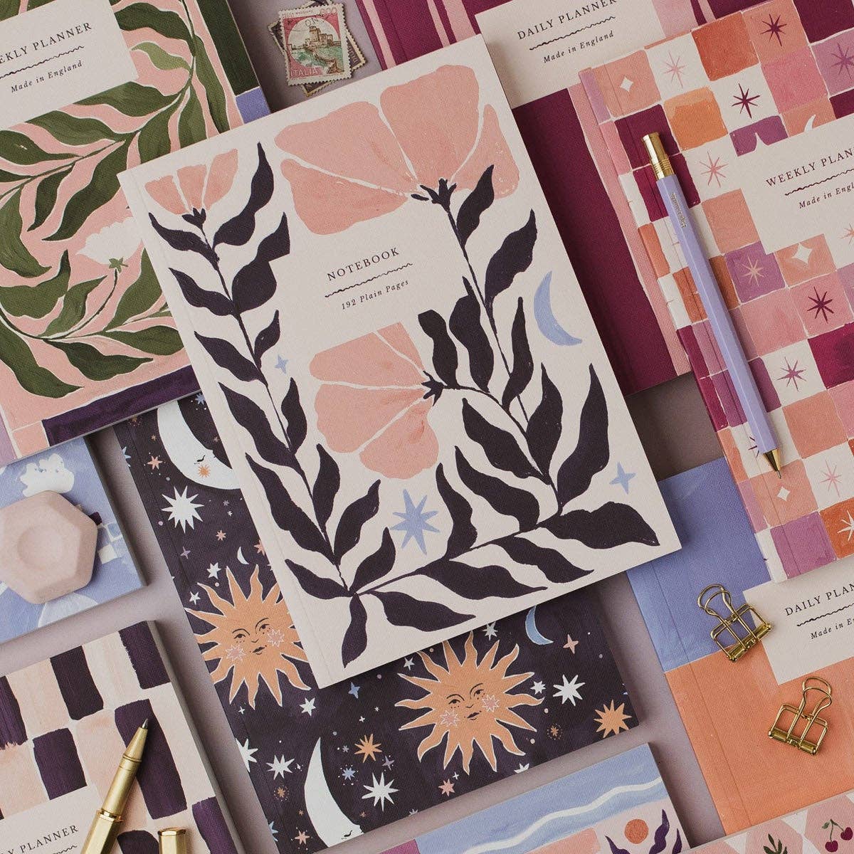 Collection of notebooks with various designs including floral, celestial, and geometric patterns.