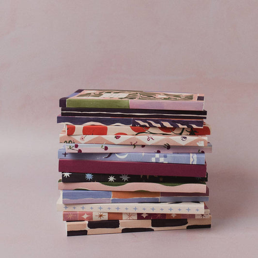 Stack of books with colorful covers on a light pink background