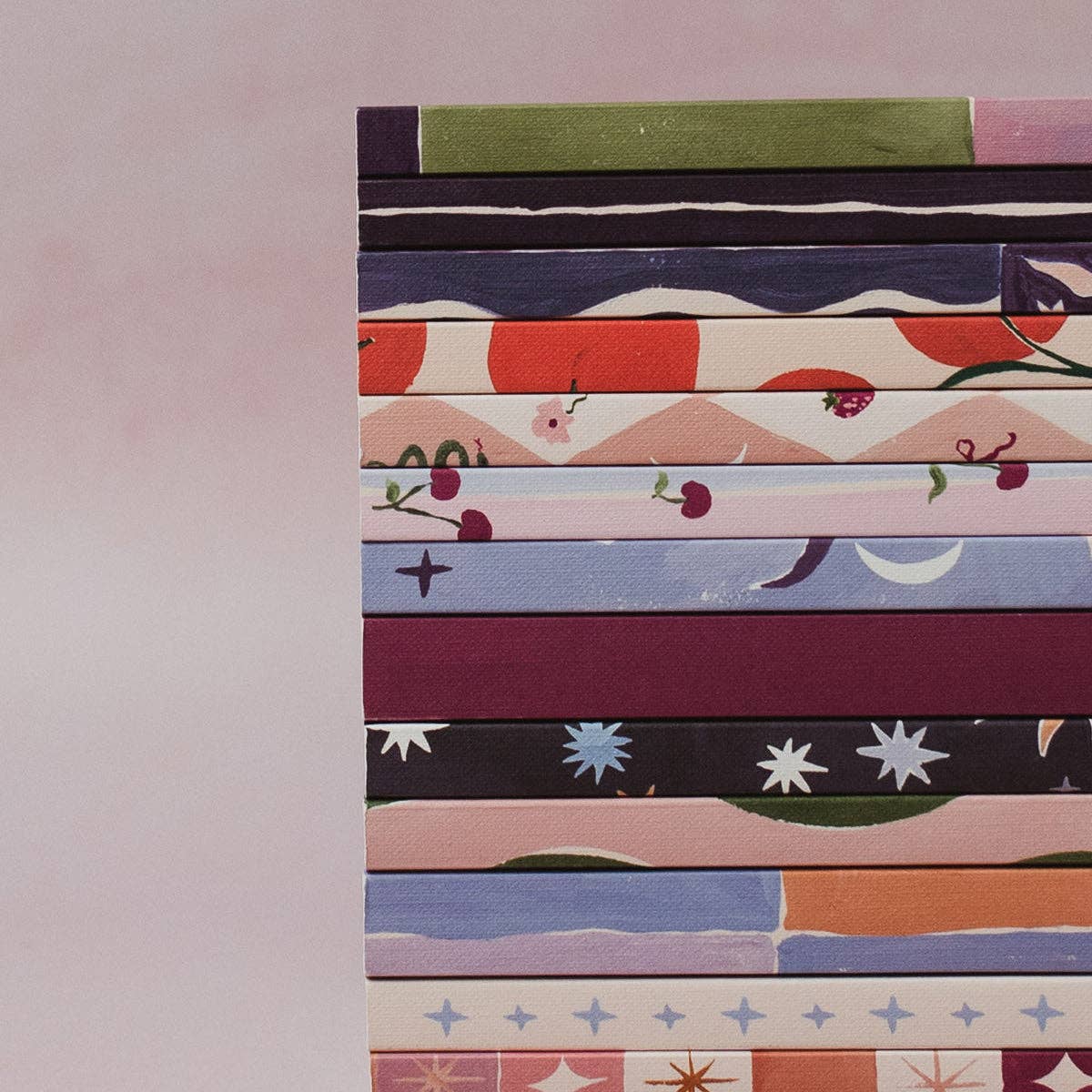 Stack of colorful patterned books on a light pink background