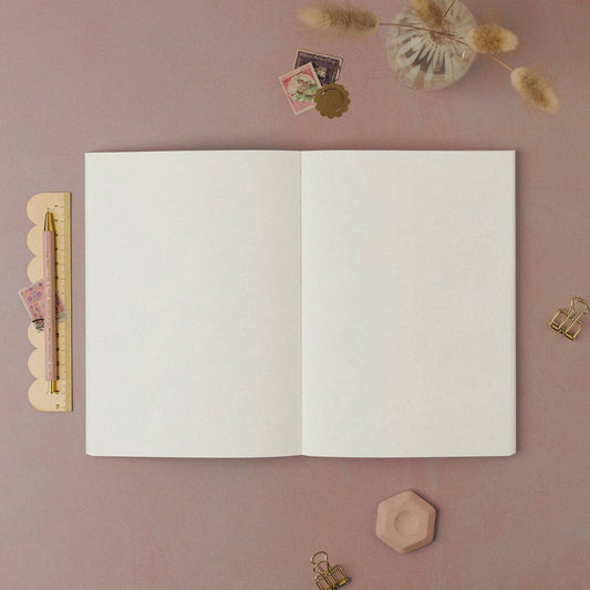 Open notebook on a pink surface with decorative items