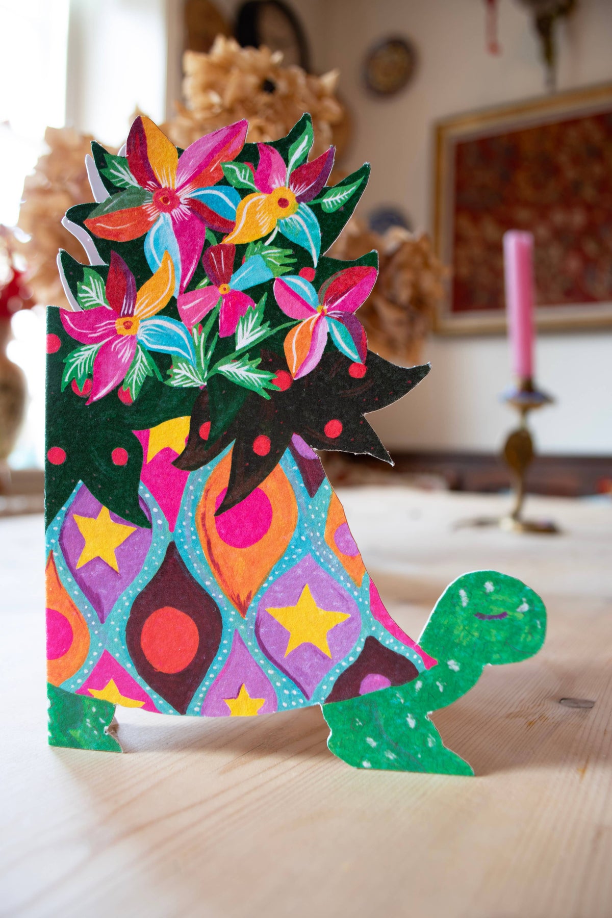 Colorful paper cutout of a cat with floral patterns on a wooden surface.