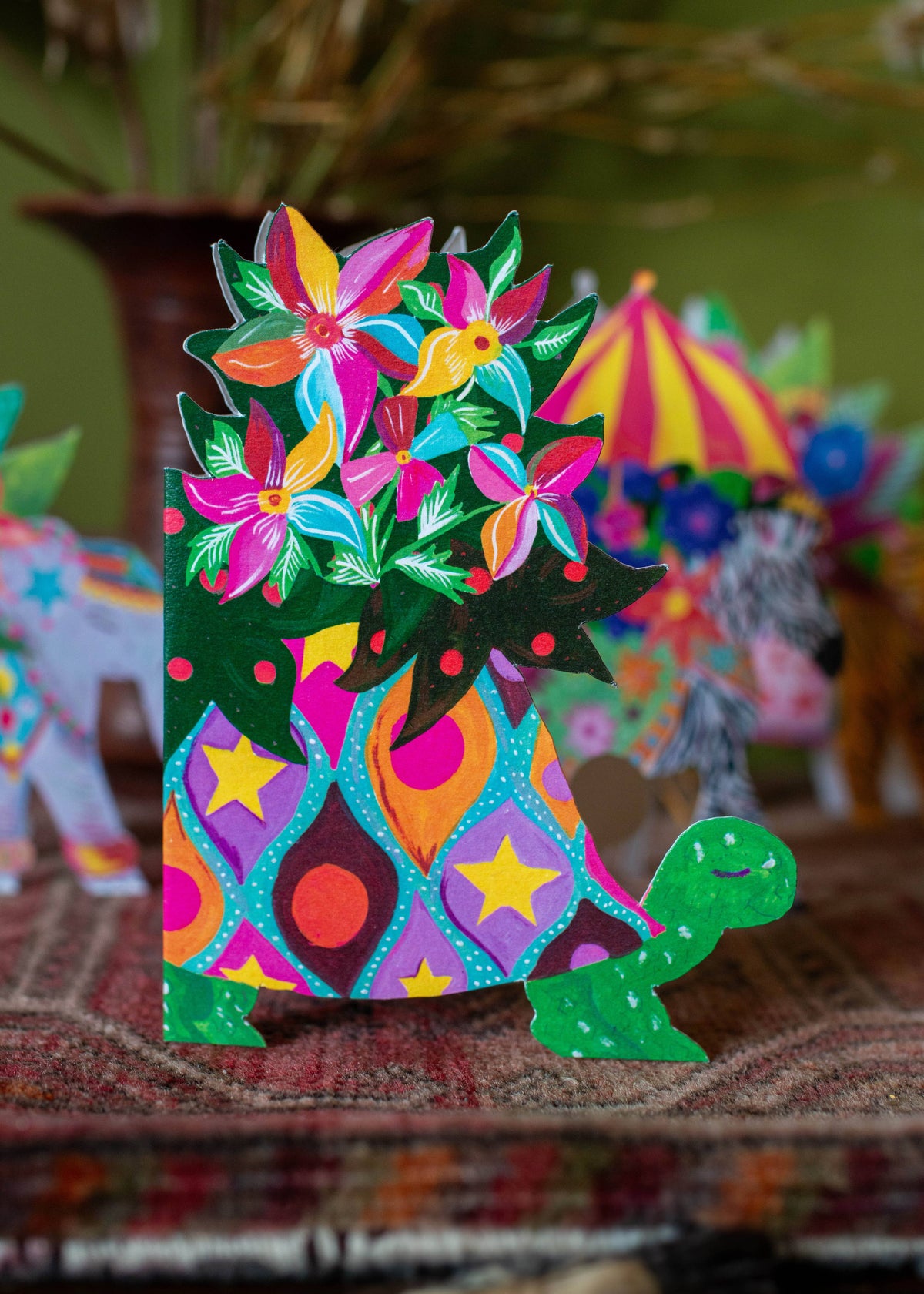 Colorful paper turtle with flowers on a patterned surface