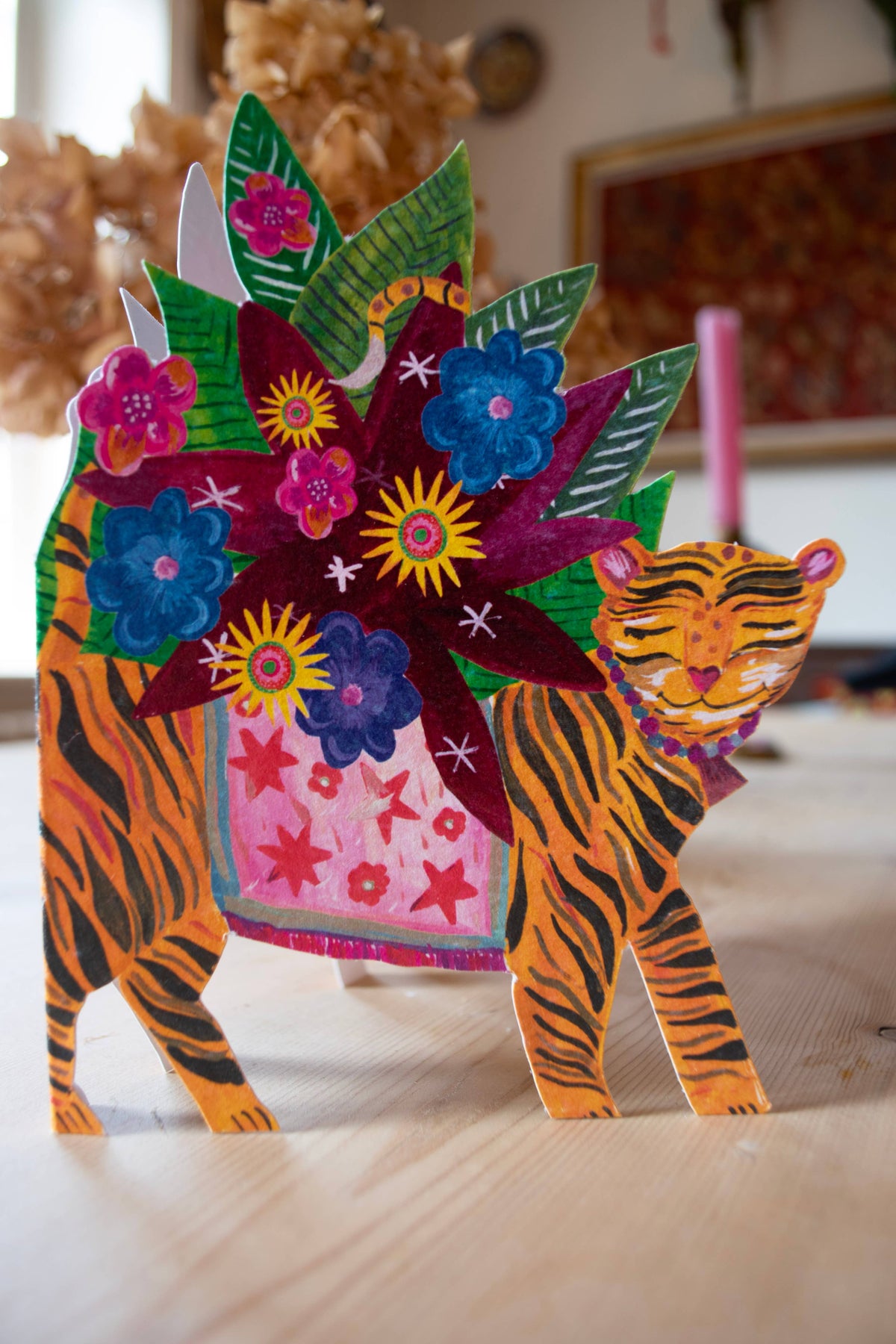 Colorful paper tiger with floral decorations on a wooden surface