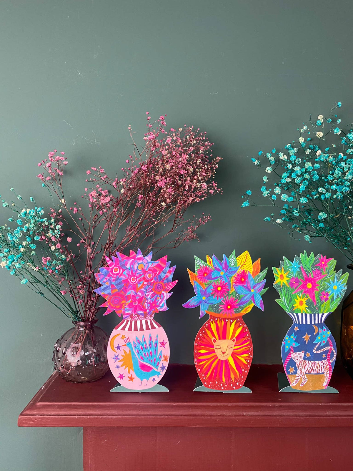Colorful decorative vases on a wooden surface with a green wall background