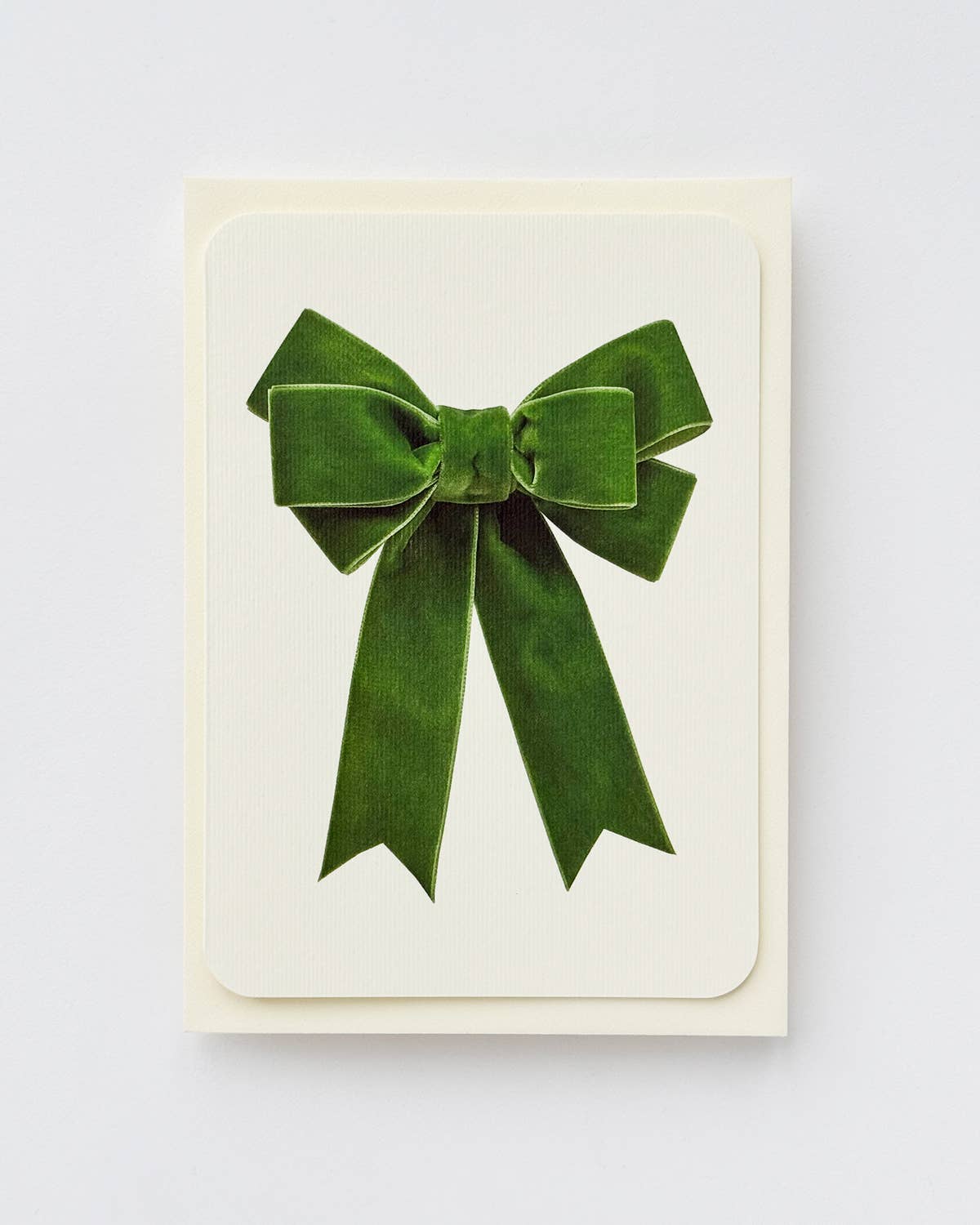 Green velvet bow on a white card with a light gray background
